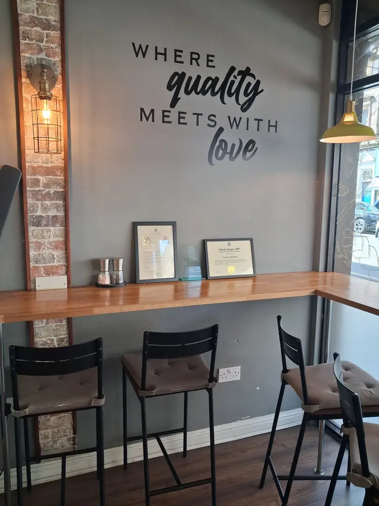 Window bar seating under a Where quality meets with love wall sign, with framed local awards on the shelf